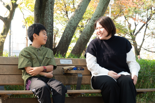 男の子とお母さんが公園のベンチで座りながら話をしている