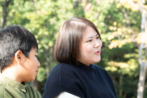 公園のベンチで座りながら話をしているお母さんと横に座る男の子