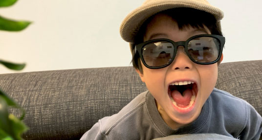 子供が家の中でソファに座って大人用のサングラスをかけている