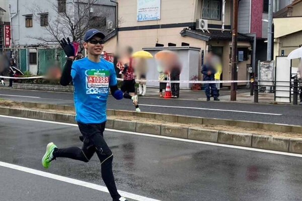 雨の中を走るマラソンランナー。サングラスとキャップを着用し、集中して走る姿。